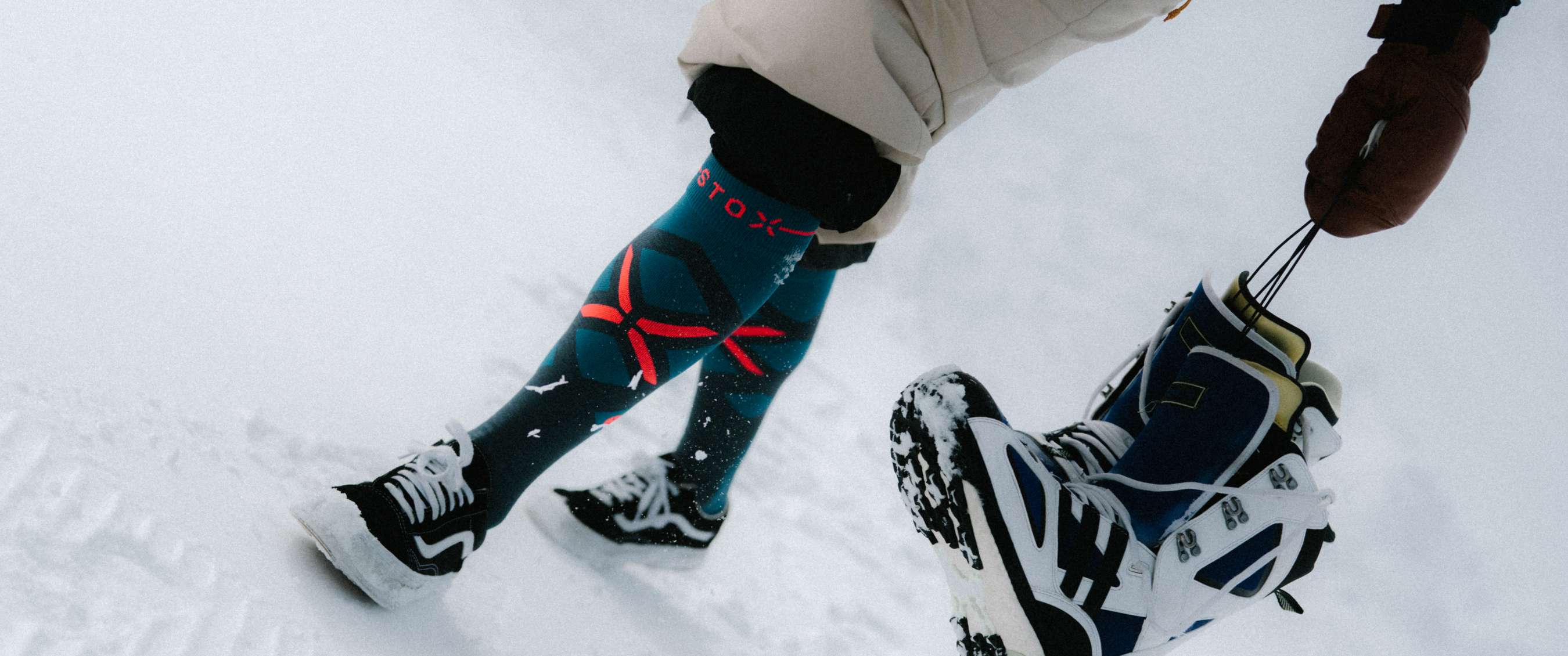 Gros plan de jambes dans la neige avec chaussettes techniques STOX et chaussures