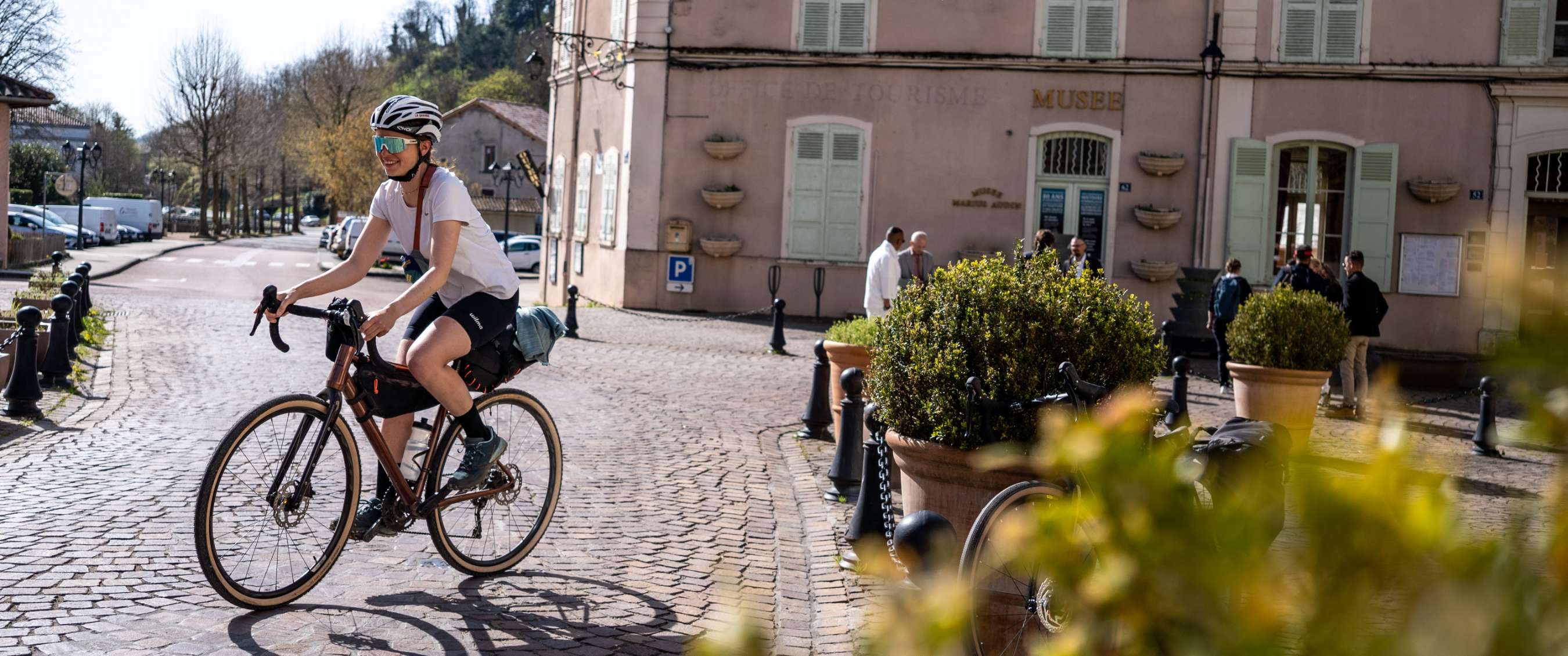 Cycliste sur une place pavée devant un bâtiment portant l’inscription MUSEE.