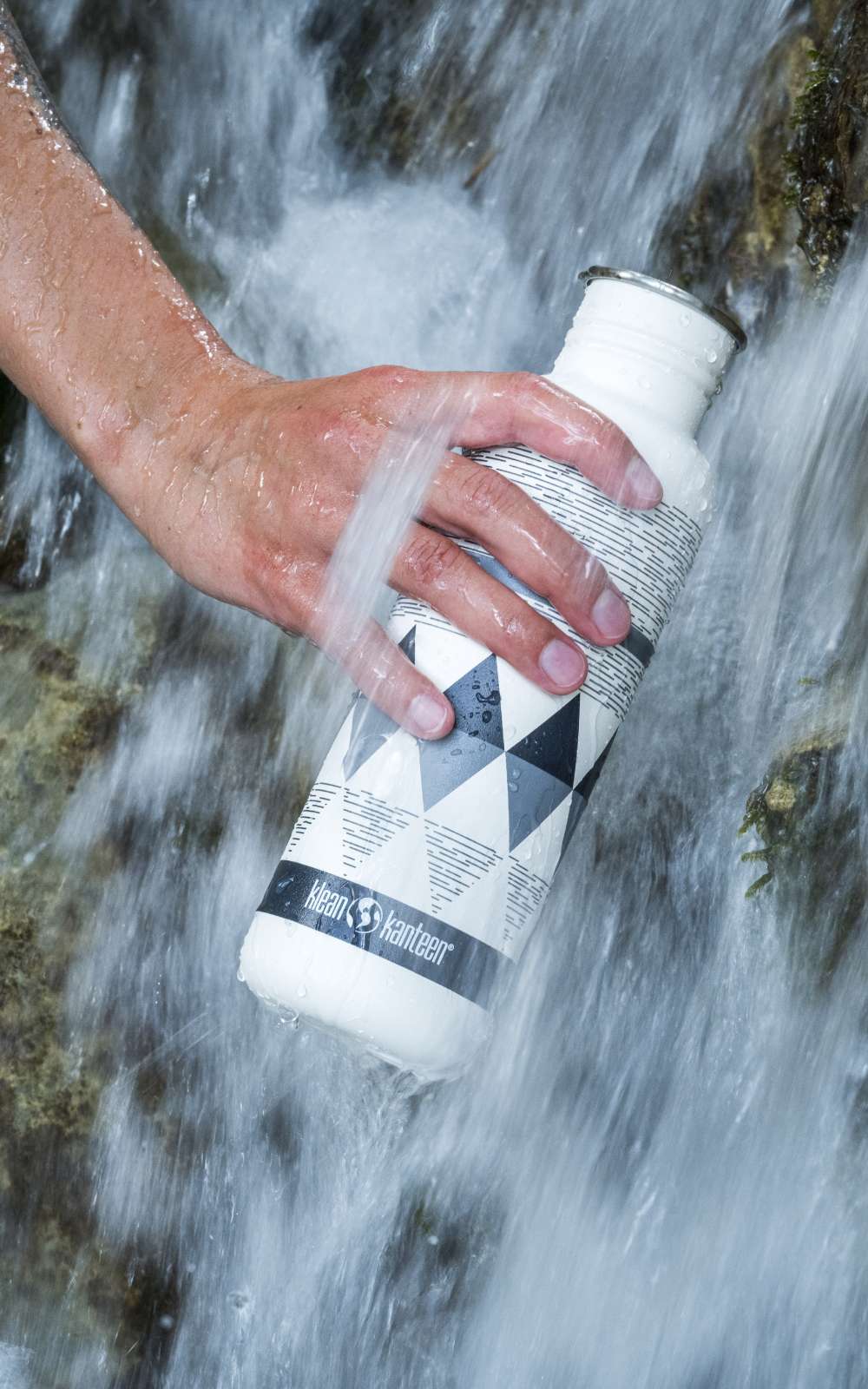 Gourde blanche avec logo Klean Kanteen tenue dans un courant d’eau.