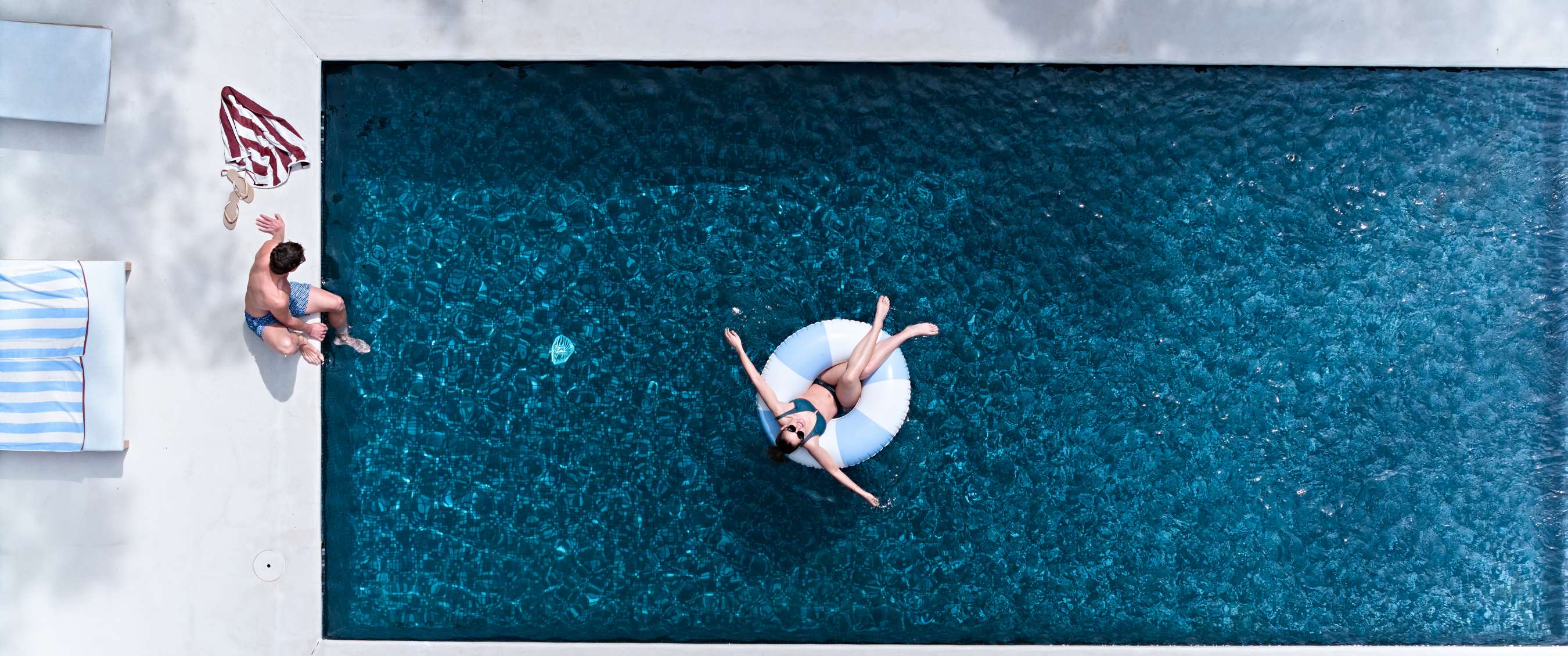 ue du dessus d’une piscine avec une femme sur une bouée et un homme au bord