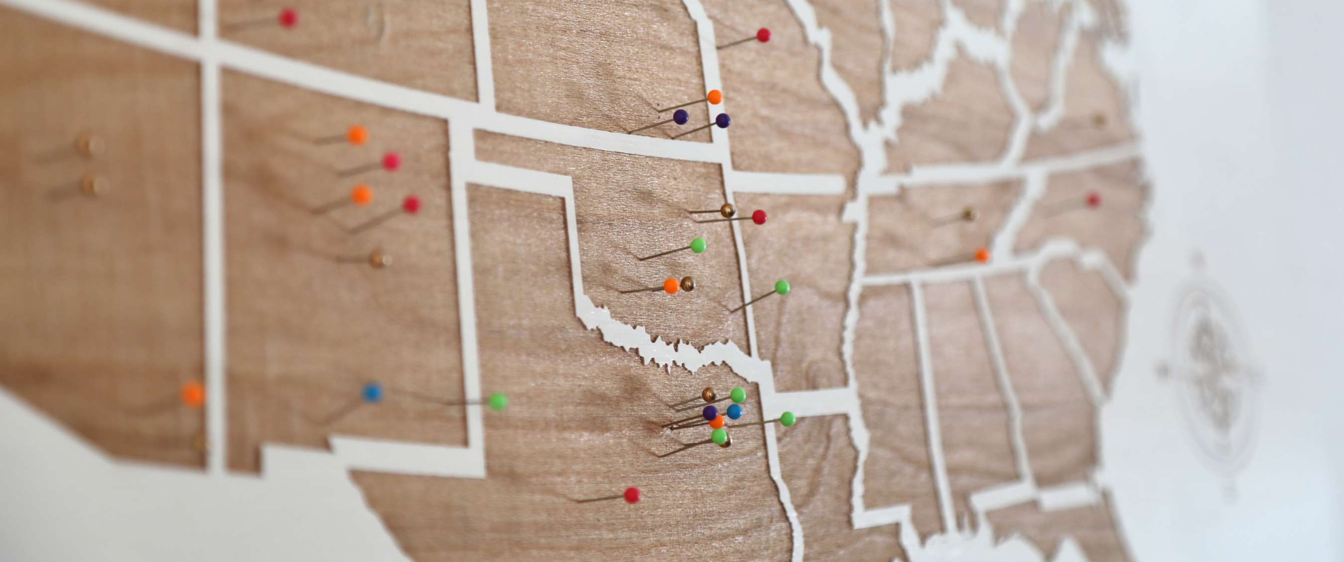 Carte du monde en bois avec frontières blanches et punaises colorées