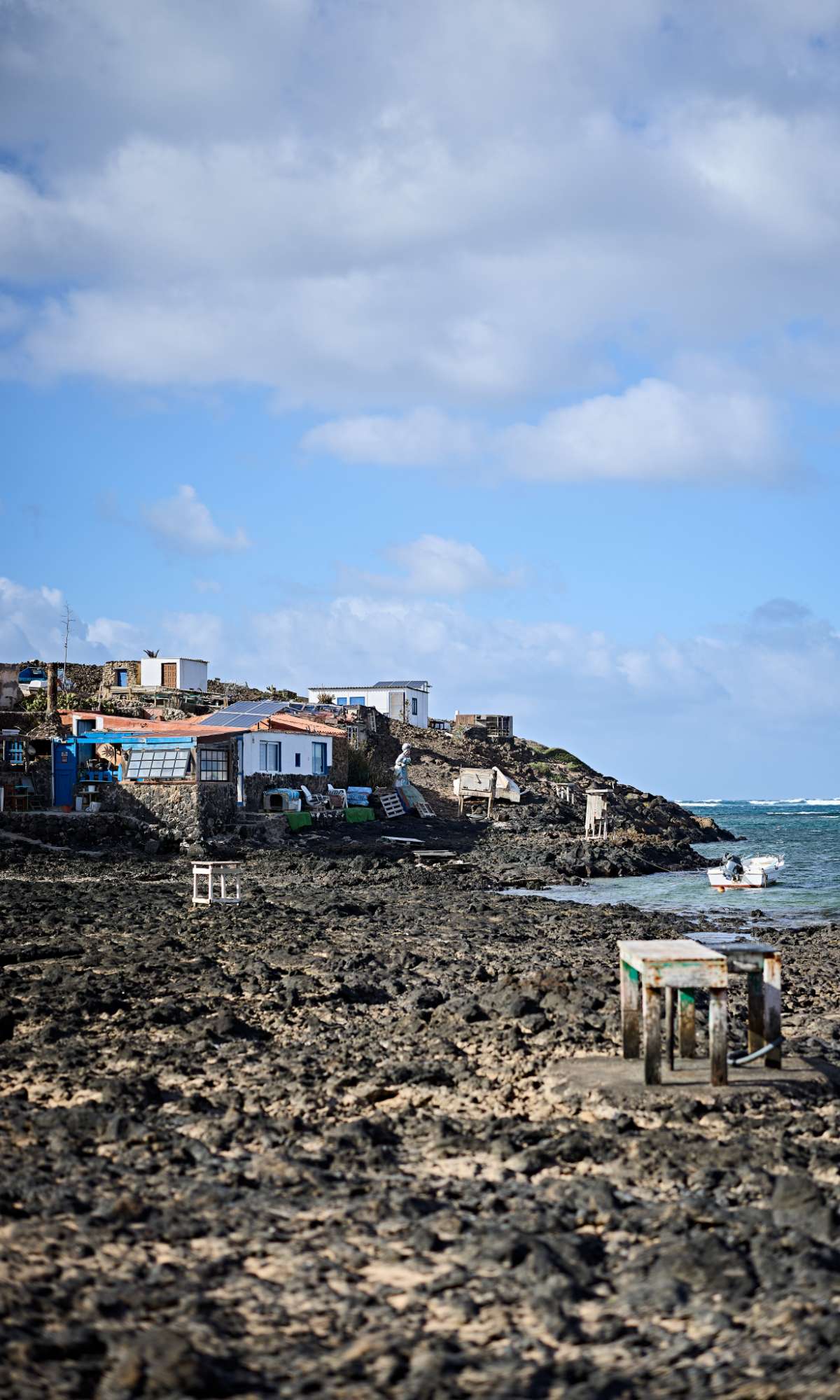 Maisons sur une côte rocheuse au bord de la mer sous un ciel bleu nuageux.