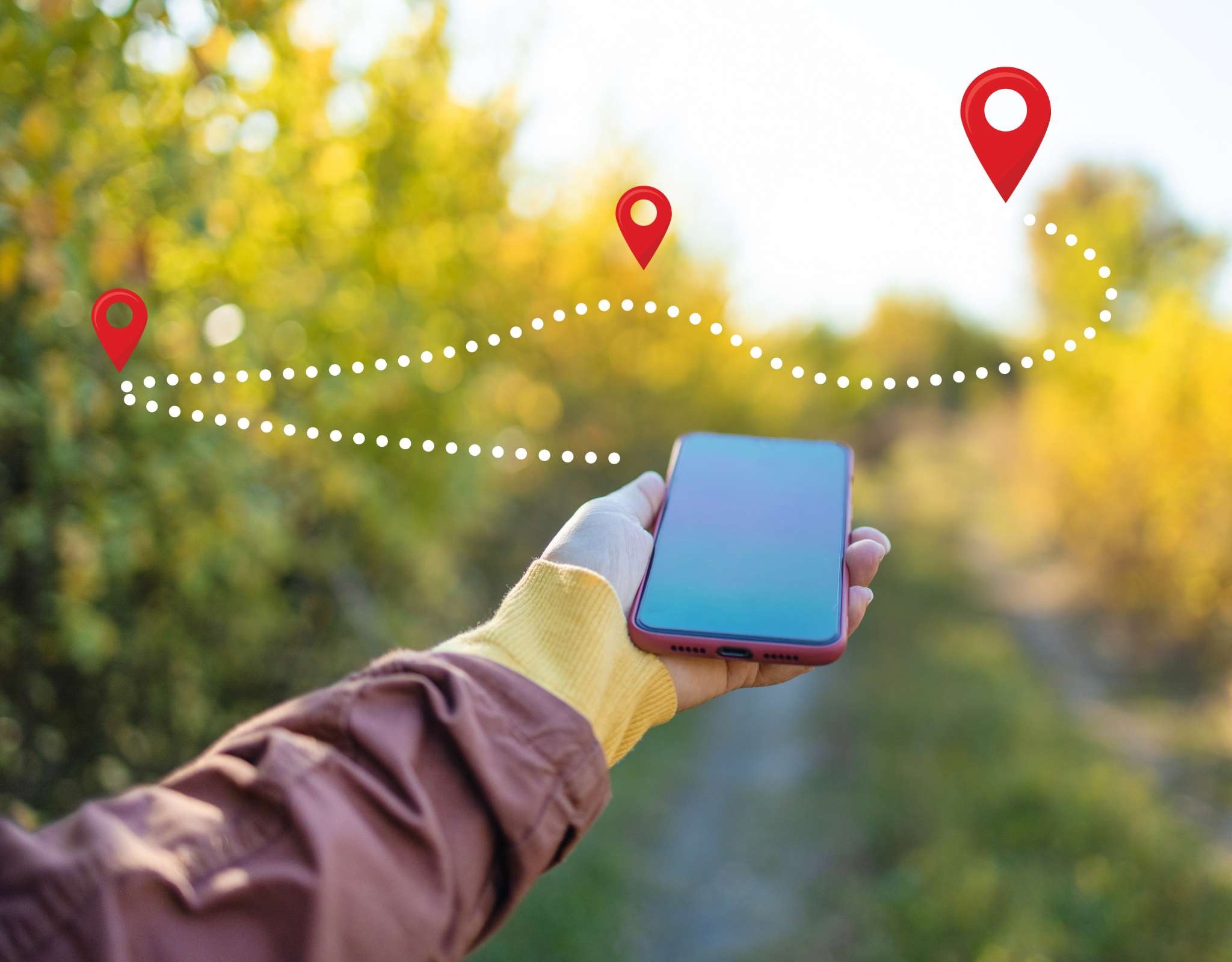 Smartphone tenu en main avec un trajet GPS visuel et des repères au-dessus d’un sentier boisé