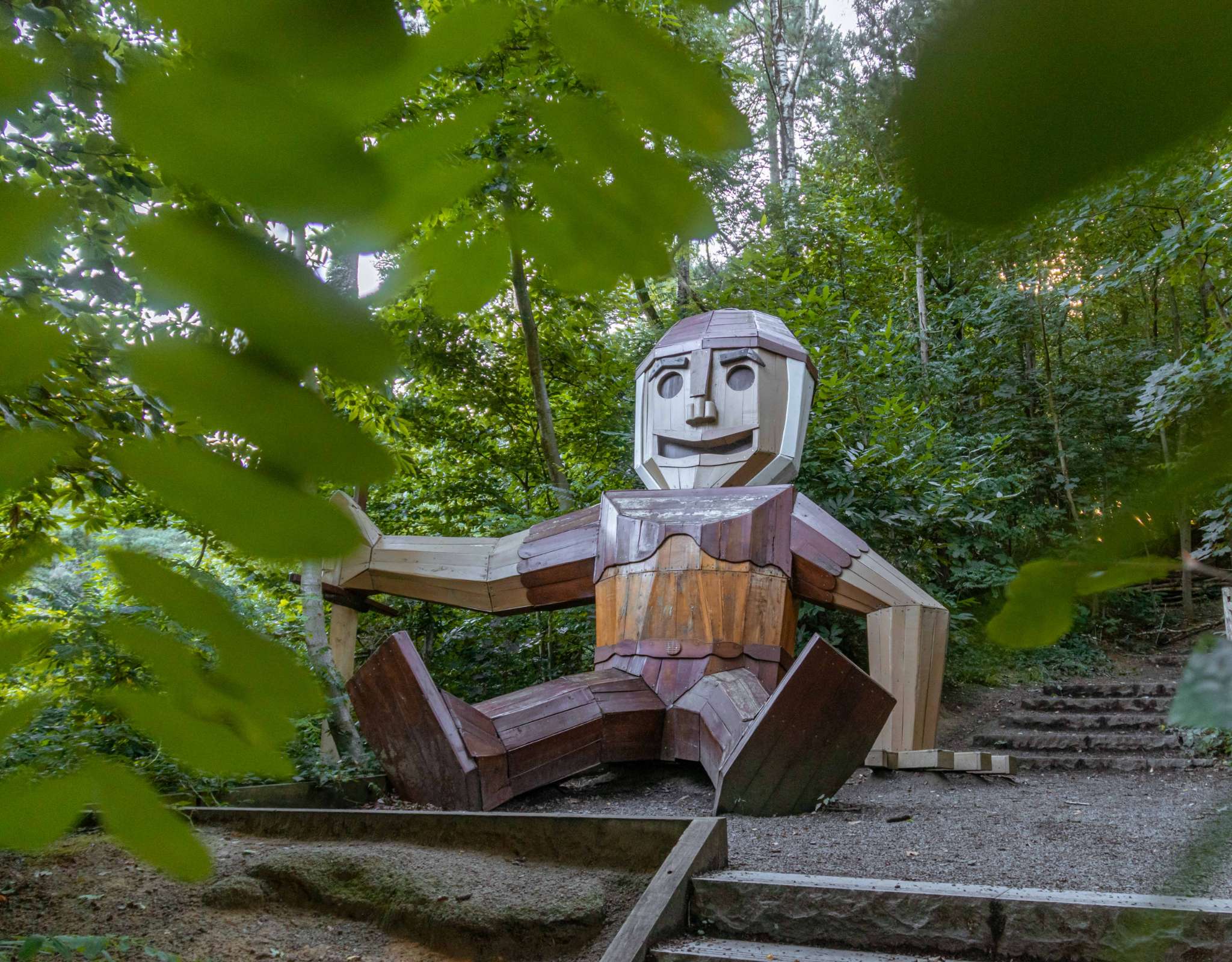 Sculpture en bois représentant une figure assise le long d’un sentier forestier